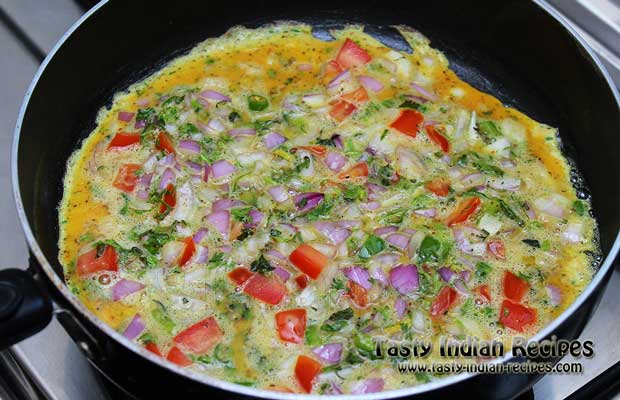 Spread egg mixture evenly and cook it on low flame for few minutes, till the eggs are set and omelette is well cooked from top