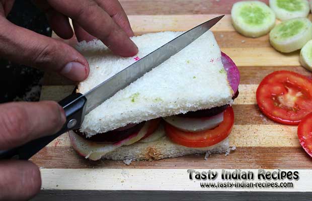 Cover the sandwich with another bread slice and press it lightly to cut into two pieces Cover the sandwich with another bread slice and press it lightly to cut into two pieces